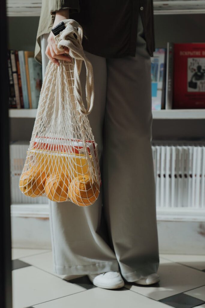 Woman holding a string bag filled with oranges, promoting eco-friendly and zero waste lifestyle.