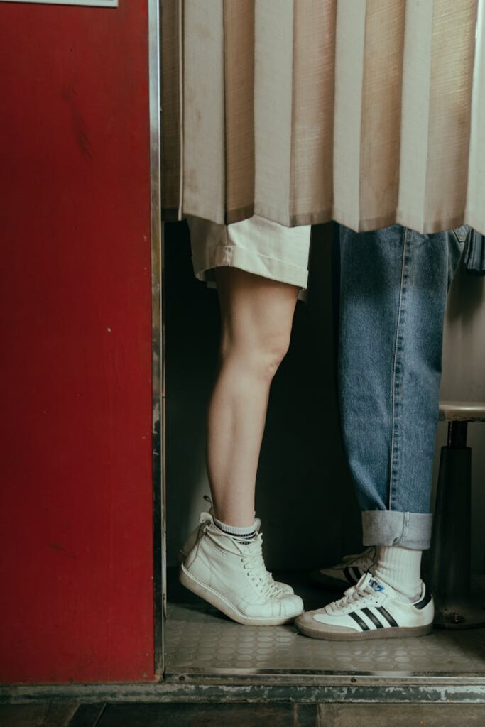 Romantic moment with teens in a vintage photobooth, denim and sneakers visible.