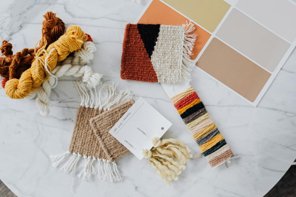 Flat lay of yarn samples and color swatches on a marble table, perfect for crafting inspiration.
