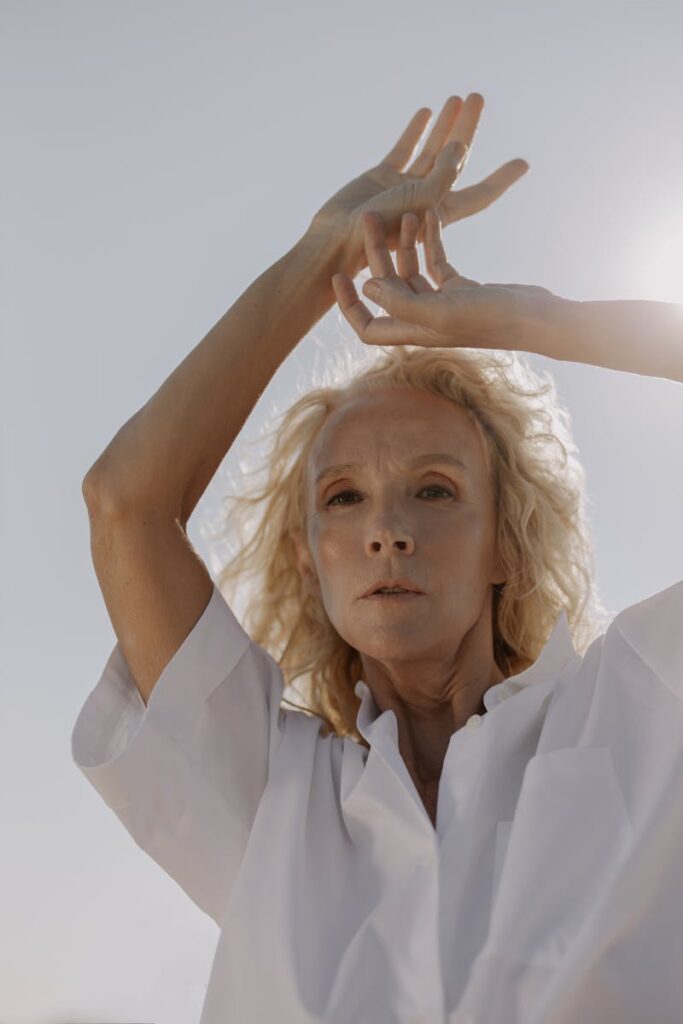 A graceful senior woman poses outdoors in stylish fashion under daylight.