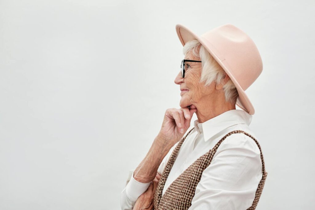 Side profile portrait of a stylish senior woman in a pink hat and glasses, exuding elegance and wisdom.