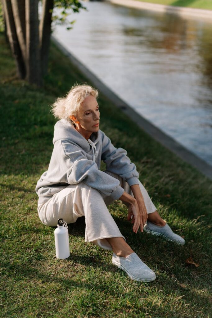 Elderly woman enjoying leisure time in the park beside a river.
