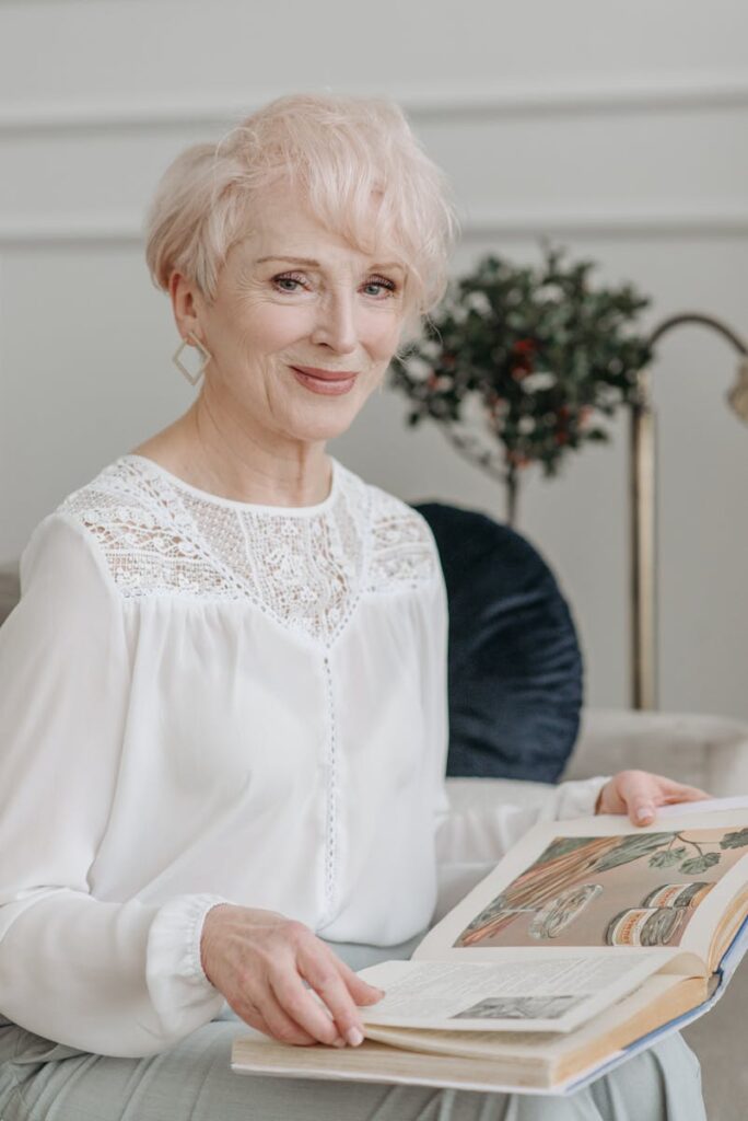 Senior woman with white hair reading a book indoors, exuding elegance and tranquility.