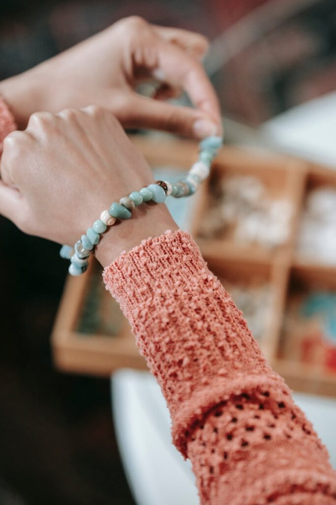 Close-up of hands wearing a beaded bracelet, showcasing handicraft and lifestyle indoors.