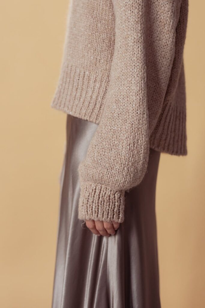 Close-up of a model wearing a knit sweater with a satin skirt, showcasing modern fall fashion.