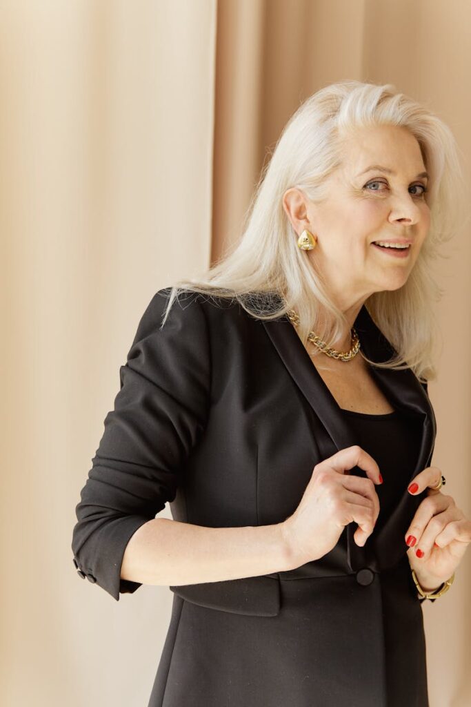 Confident senior businesswoman in a black suit posing indoors, showcasing professional elegance.