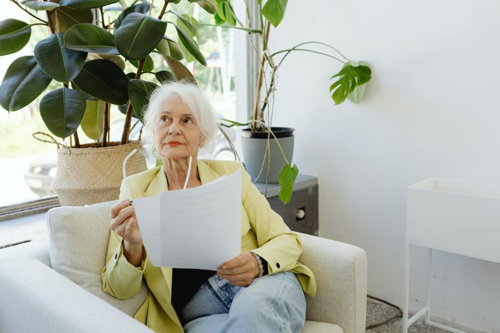 Senior woman in casual setting reviewing documents indoors.