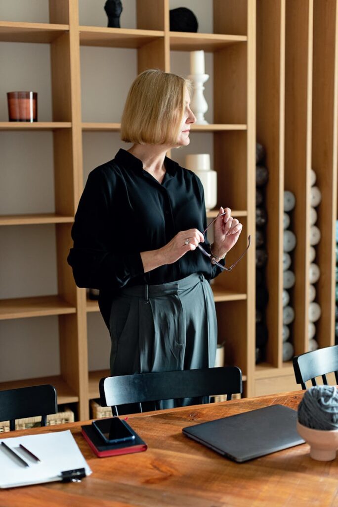 Businesswoman with blonde hair stands in a modern office. Elegant and composed.