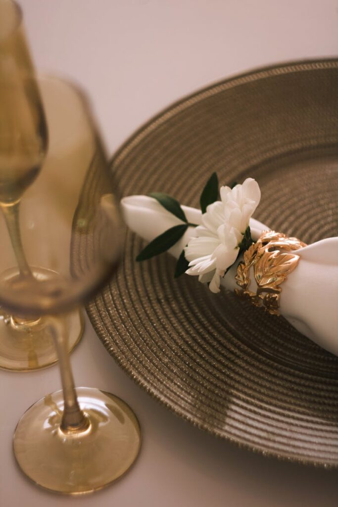 A sophisticated dining setup featuring gold accents, crystal glasses, and floral napkin decoration.