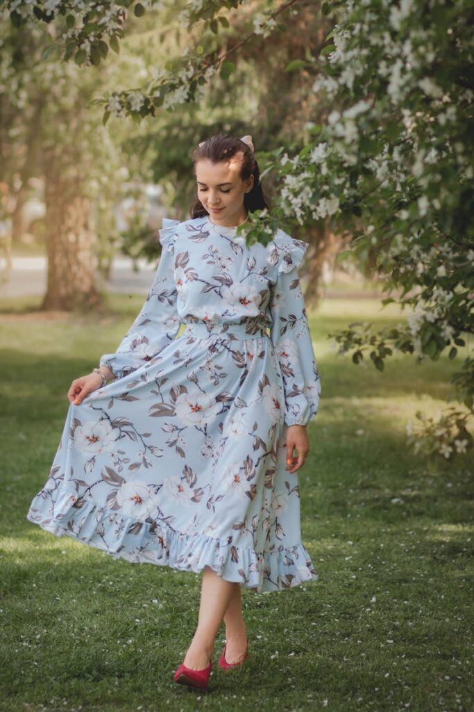 Woman in a flowing floral dress walking gracefully in a lush green park setting.