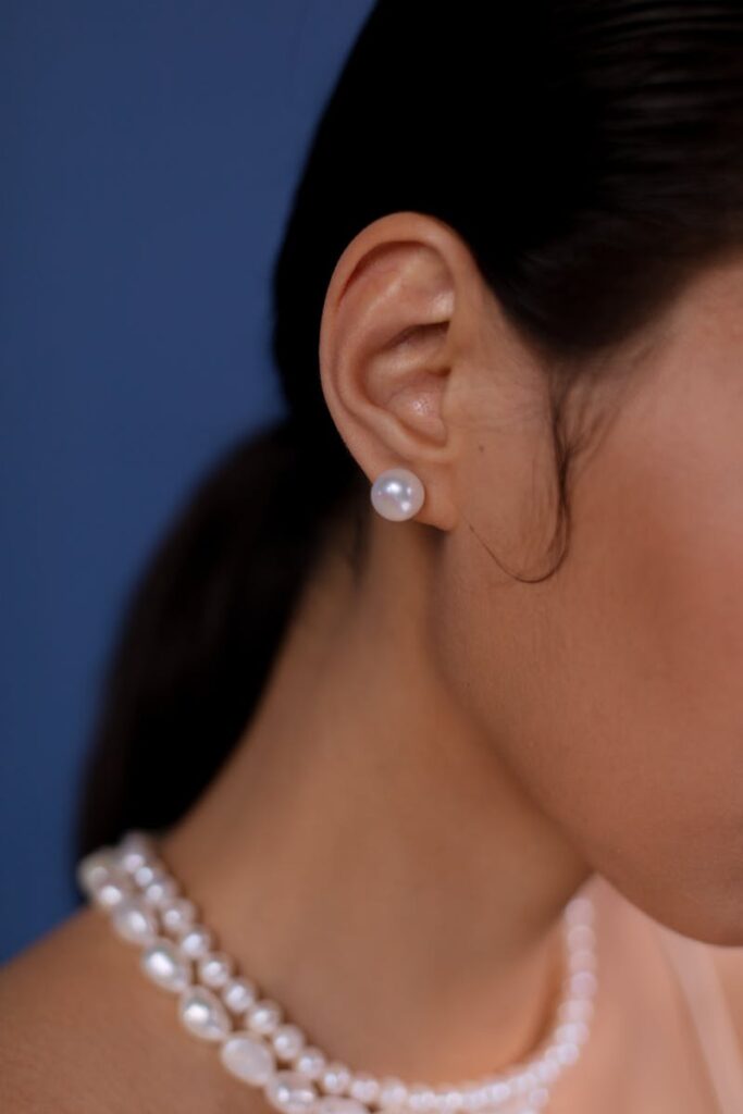 Close-up of a woman wearing elegant pearl earrings and necklace. Luxury fashion.