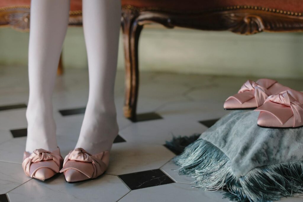 Close-up of pink satin shoes with bows, enhancing elegance in a classic interior setting.