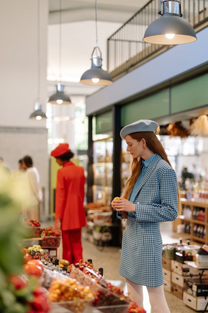 Chic woman in blue blazer and beret exploring a stylish market with fresh produce.