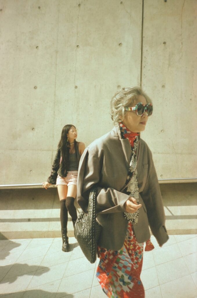 a woman walking down a sidewalk carrying a purse
