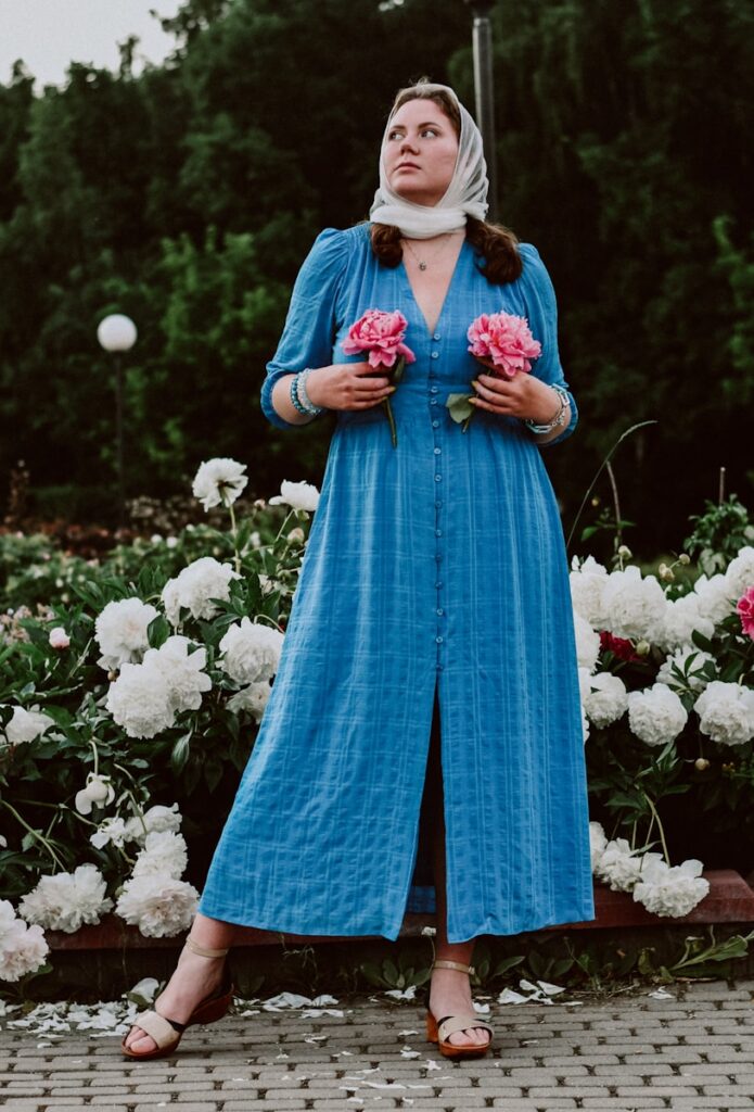 A woman in a blue dress standing in front of flowers