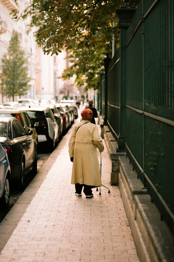 a person walking down a sidewalk with a cane