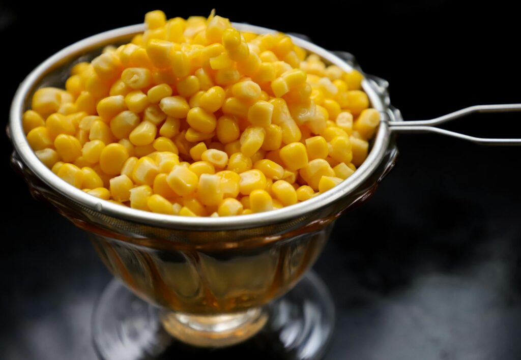 Close-up of fresh yellow corn kernels in a stainless steel bowl, perfect for food-related content.