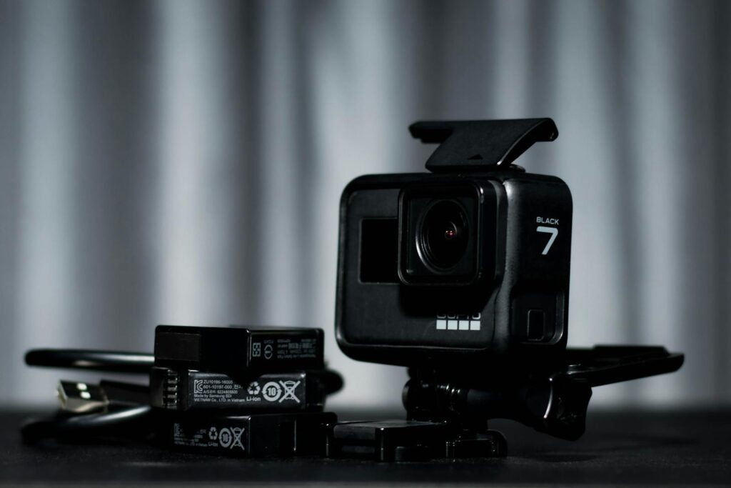 Detailed view of a black action camera and batteries on a dark background.