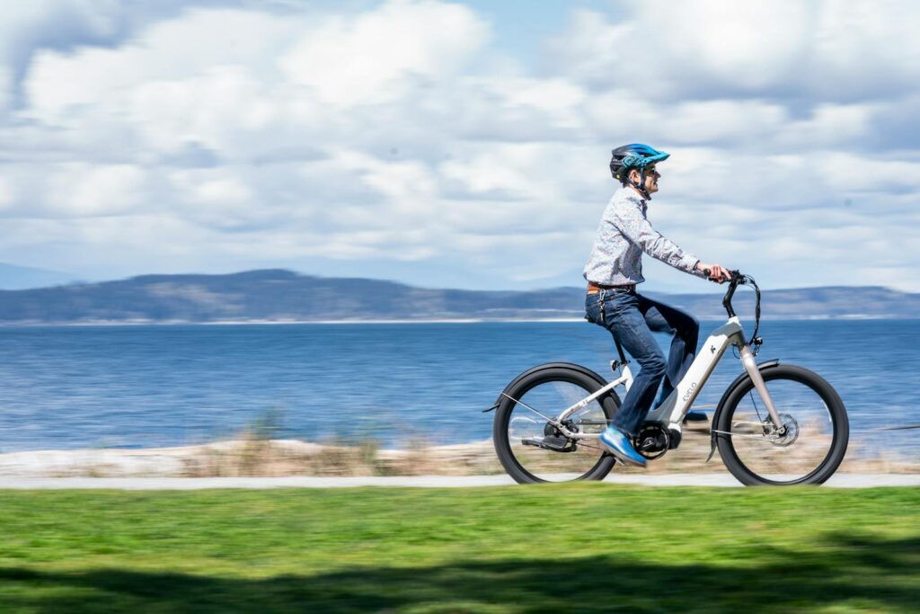 A man rides an electric bicycle along a seaside path, embracing outdoor adventure.