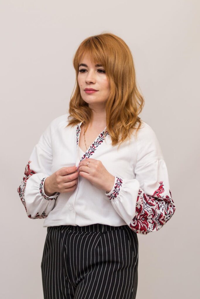 Woman in embroidered Ukrainian blouse posing indoors, showcasing traditional style.