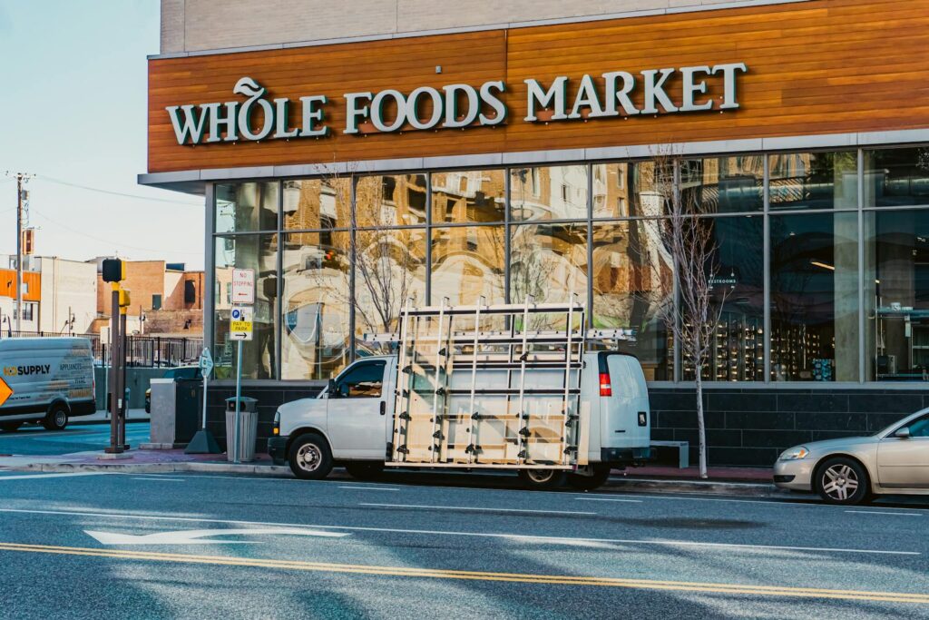 Image of Whole Foods Market with vehicles on a Baltimore street, capturing urban life.