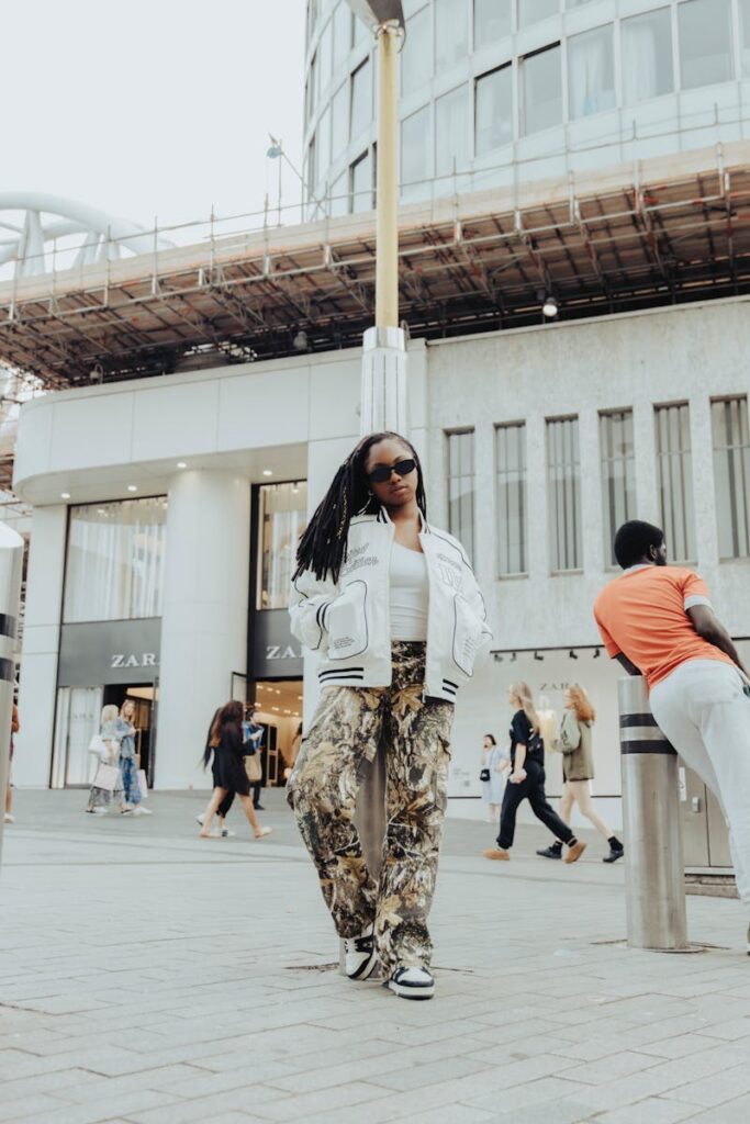 Stylish woman posing in city street, showcasing urban fashion against modern architecture.