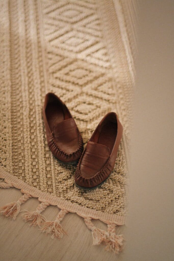 Elegant brown loafers placed on a textured handmade carpet indoors.