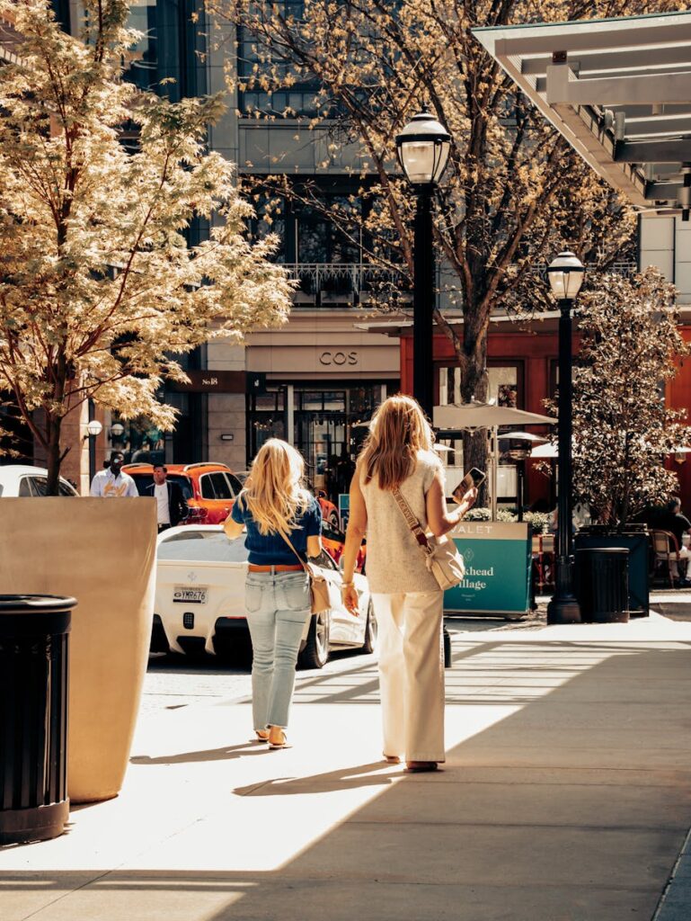 Two women walking on a sunny Atlanta street in spring, surrounded by urban architecture.