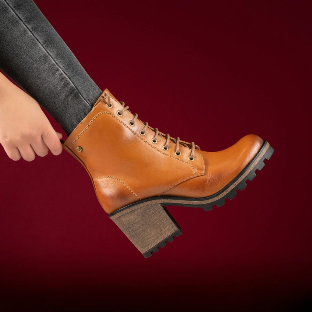 Close-up of a fashionable brown leather ankle boot with block heel, held by a person.