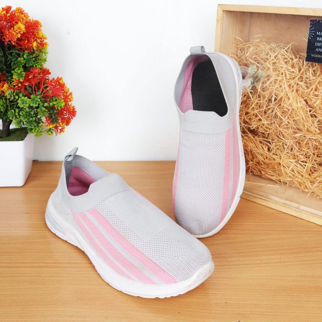 Elegant women's sneakers with pink stripes on a wooden surface, perfect for casual fashion.