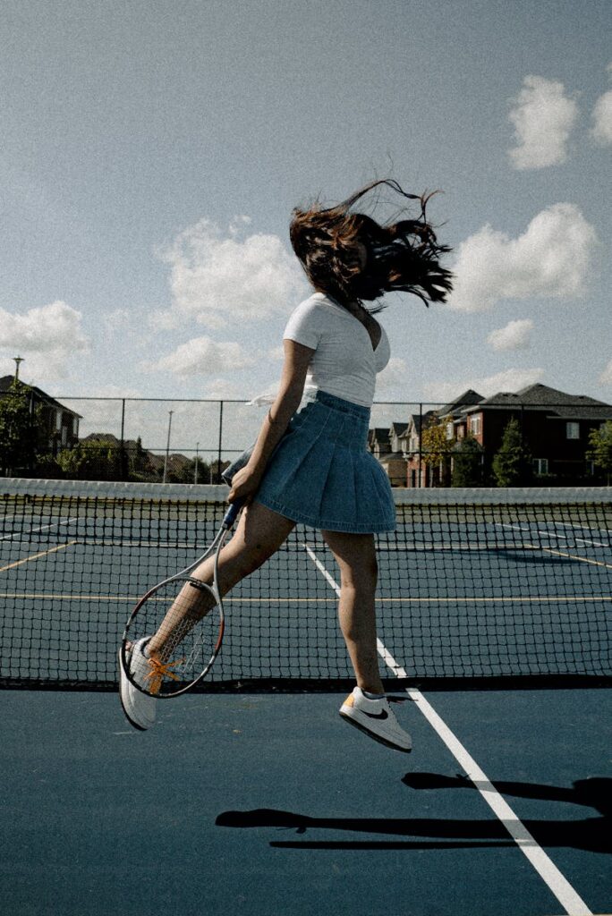 Young woman executing a powerful jump shot on an outdoor tennis court.