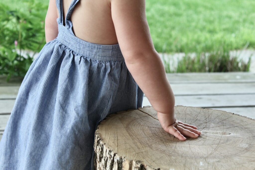woman in blue and white stripe dress sitting on brown wooden log