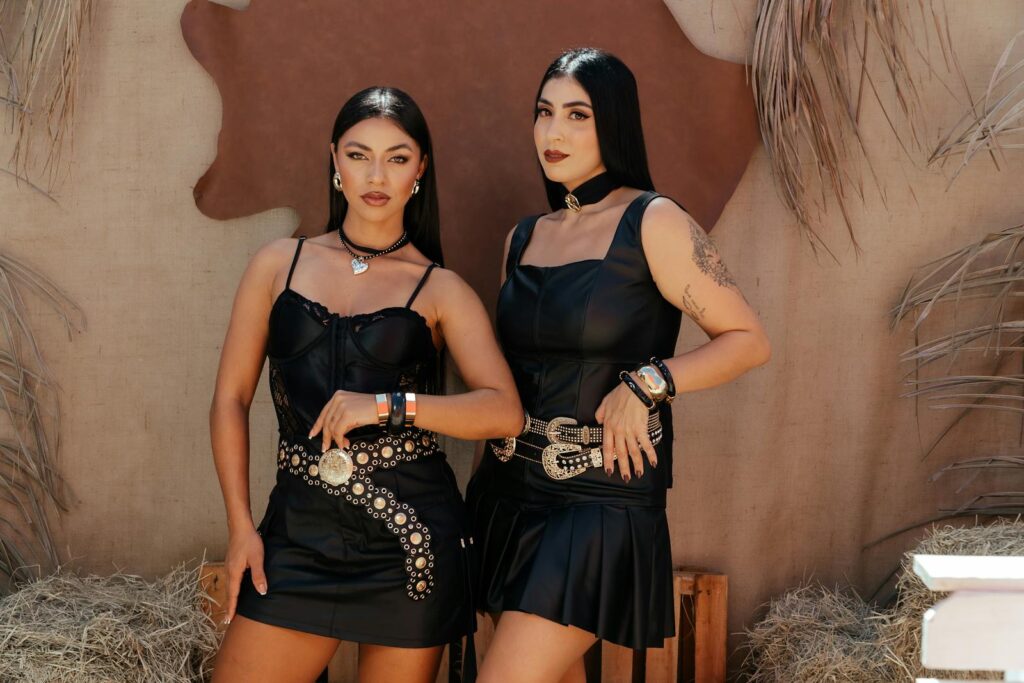 Two women in chic western outfits posing confidently against a rustic backdrop.