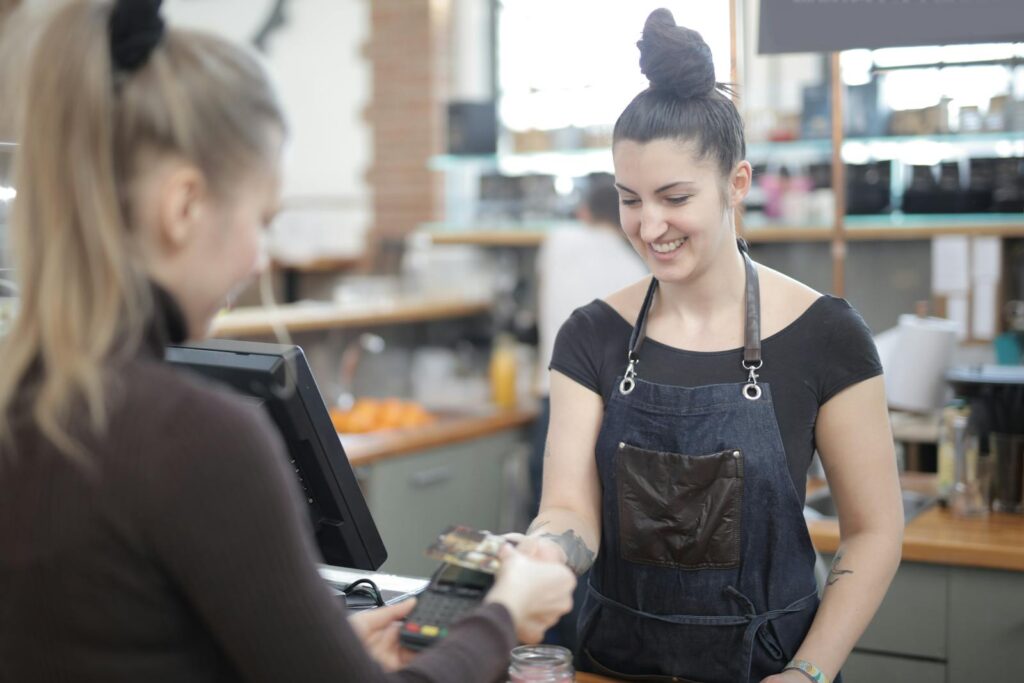 Smiling cashier helping customer with payment at store counter.
