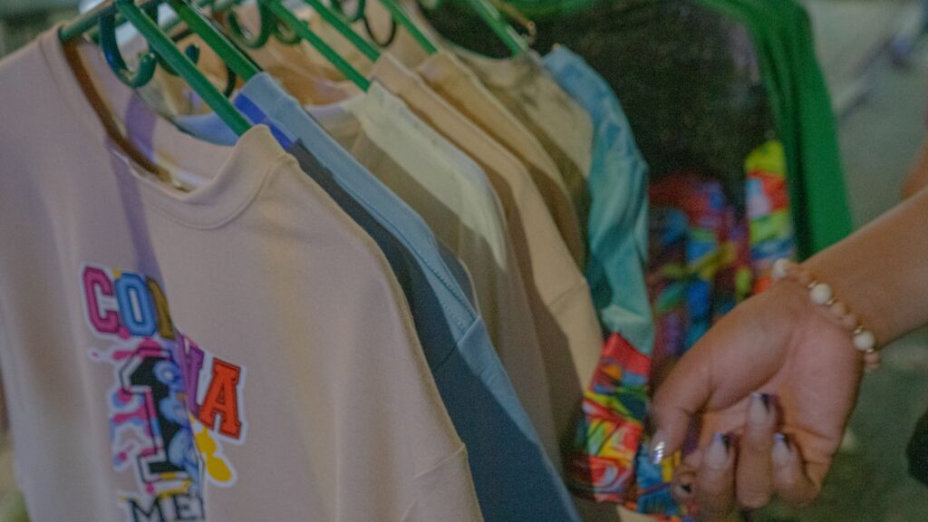 A woman is holding onto a t - shirt hanging on a rack