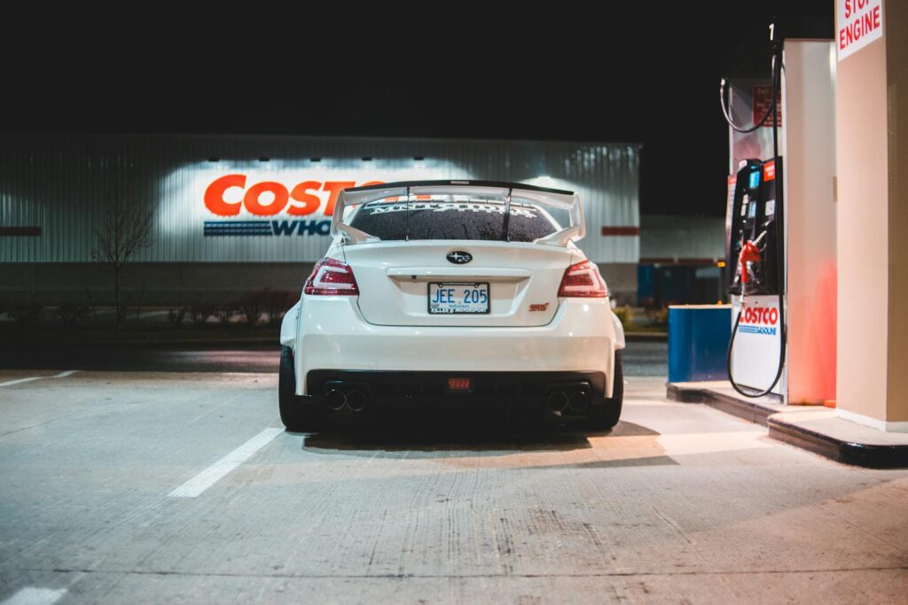 Contemporary white car parked near pump on fuel station at night in city