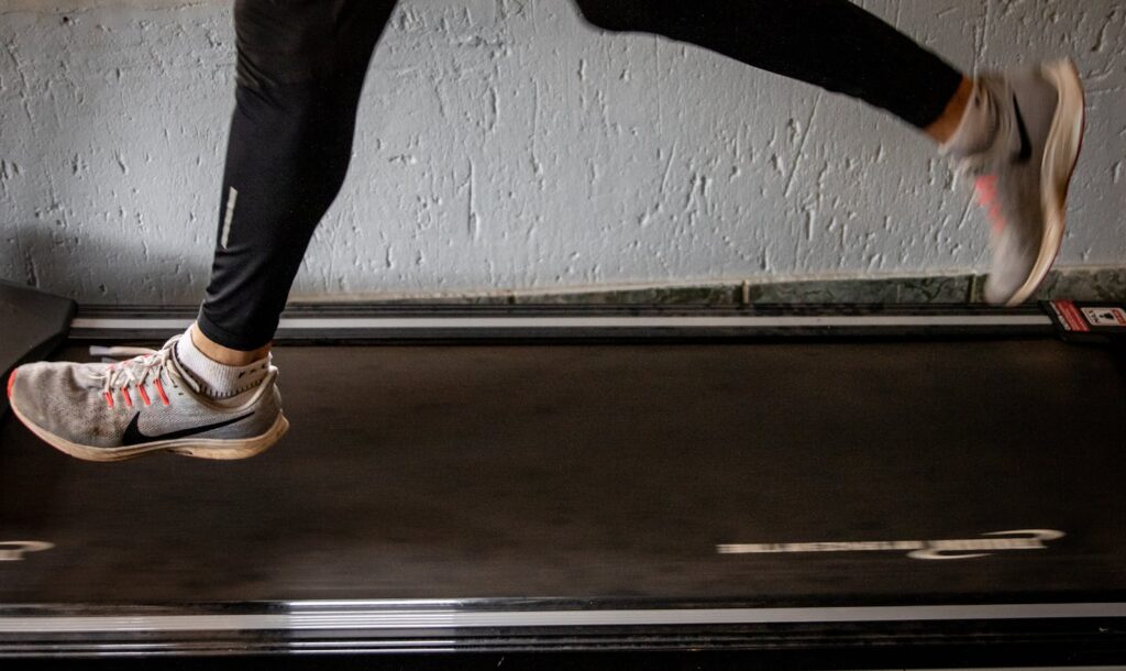 Close-up of a woman's legs running on a treadmill indoors, focusing on fitness and exercise.