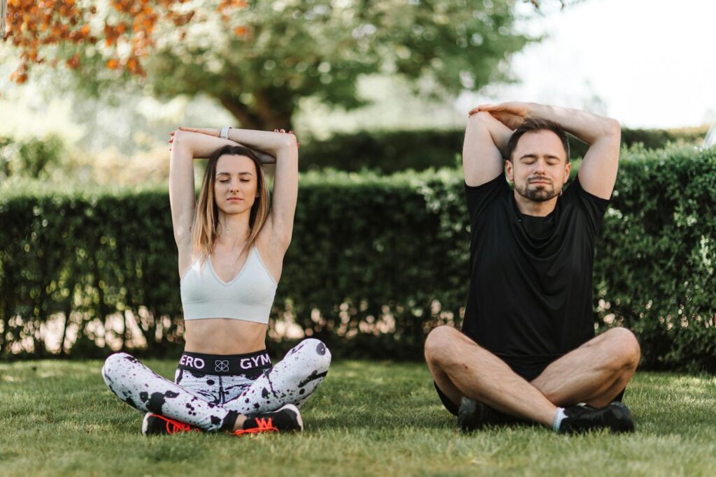 A couple practicing yoga and meditation in a serene outdoor setting, enhancing well-being.
