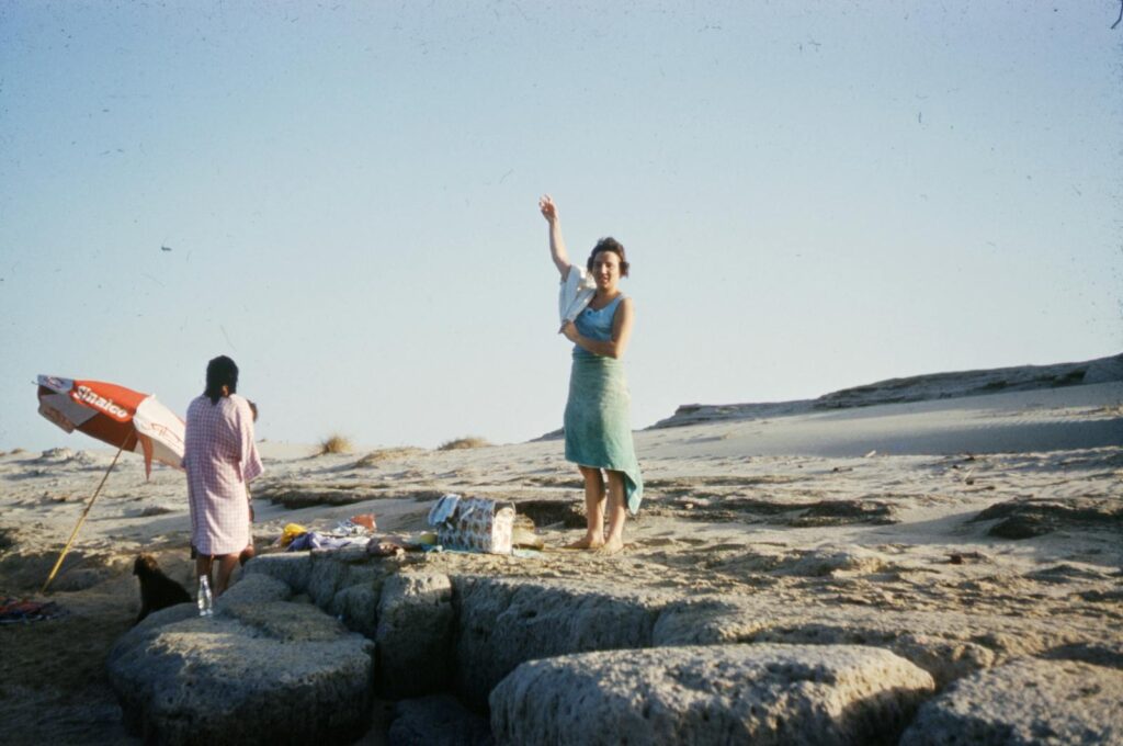 A nostalgic vintage photograph capturing people enjoying a sunny day on rocky seashore.