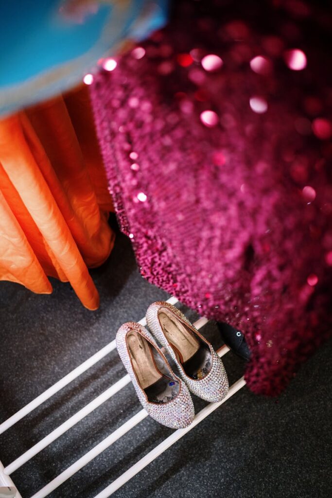 Sparkling high heels on shoe rack beneath a glimmering sequin dress showcase fashion elegance indoors.