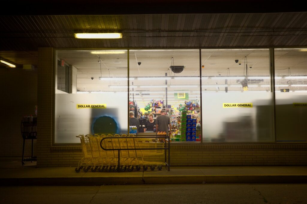 A store front at night with people walking by