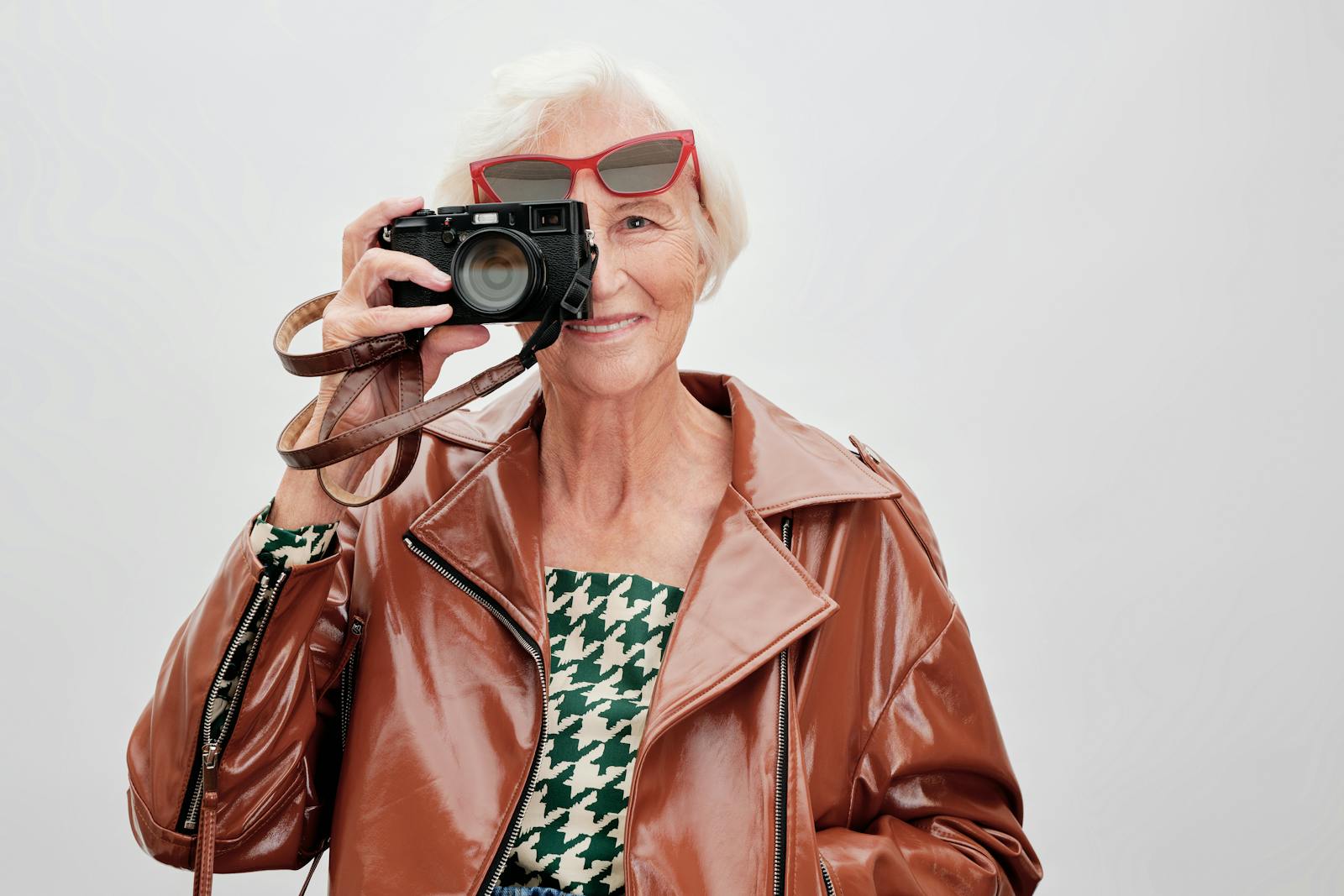 Elegant senior woman with camera and sunglasses captures the moment with style.