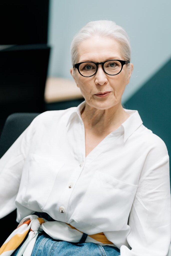 Stylish senior woman in glasses showcasing confidence in a professional office environment.