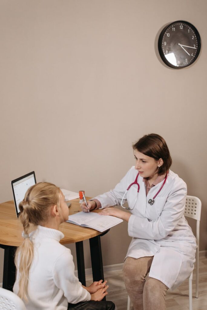 A pediatrician consults with a child in a clinic setting, focused on healthcare.