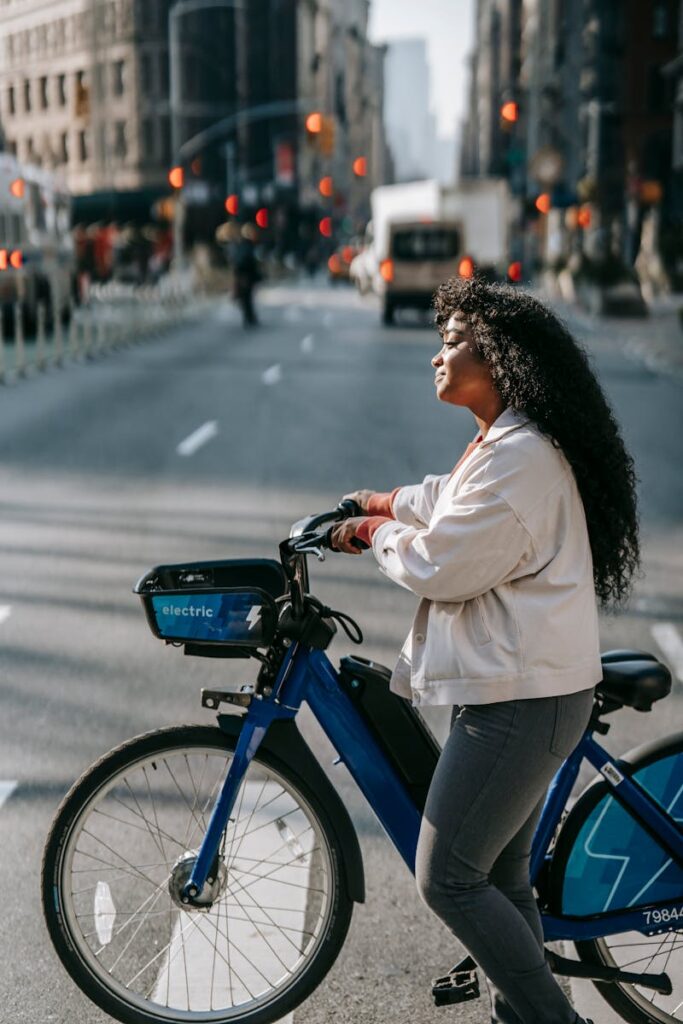 Confident young woman biking through a busy city street during the day.