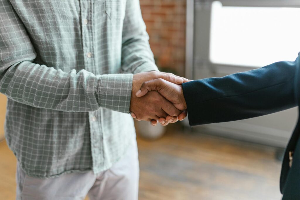 Close-up of two business professionals shaking hands in a modern office environment.