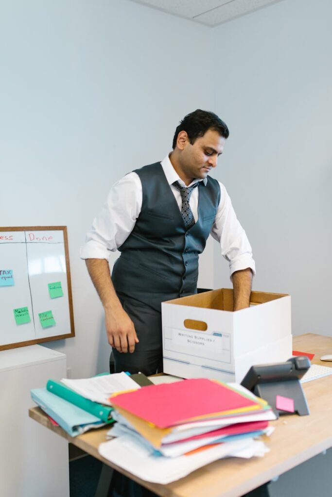 Professional man packing belongings into a box at an office desk, preparing to leave the workplace.