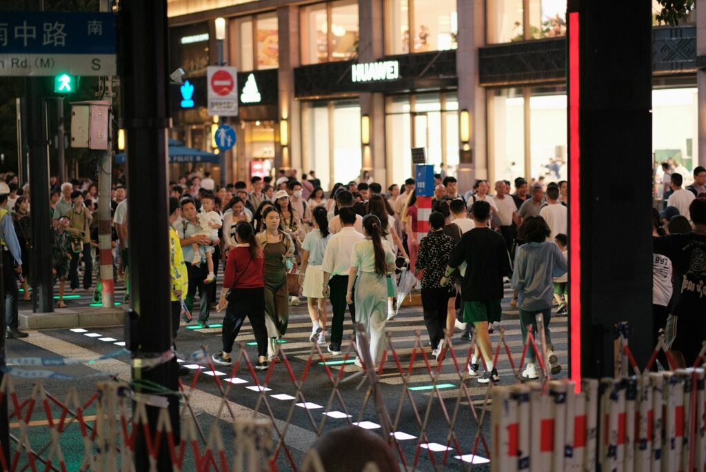A crowd of people walking across a street at night