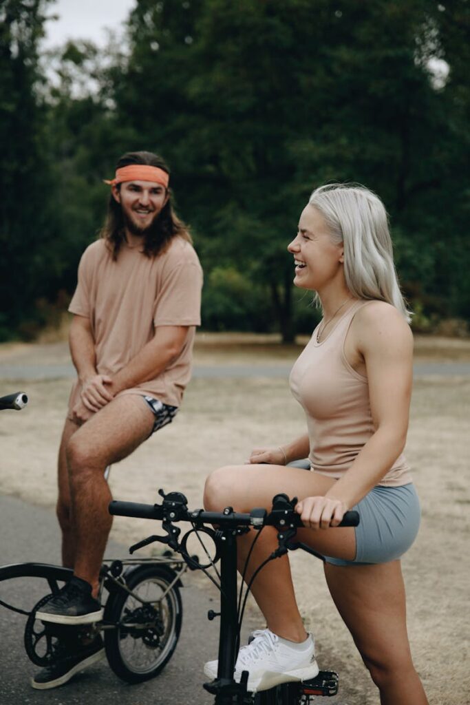 A young couple enjoying a relaxed bike ride and conversation in a scenic park setting.