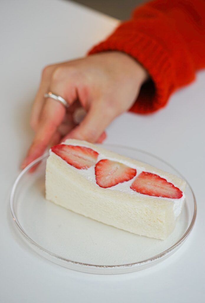 a person cutting a piece of cake with a knife